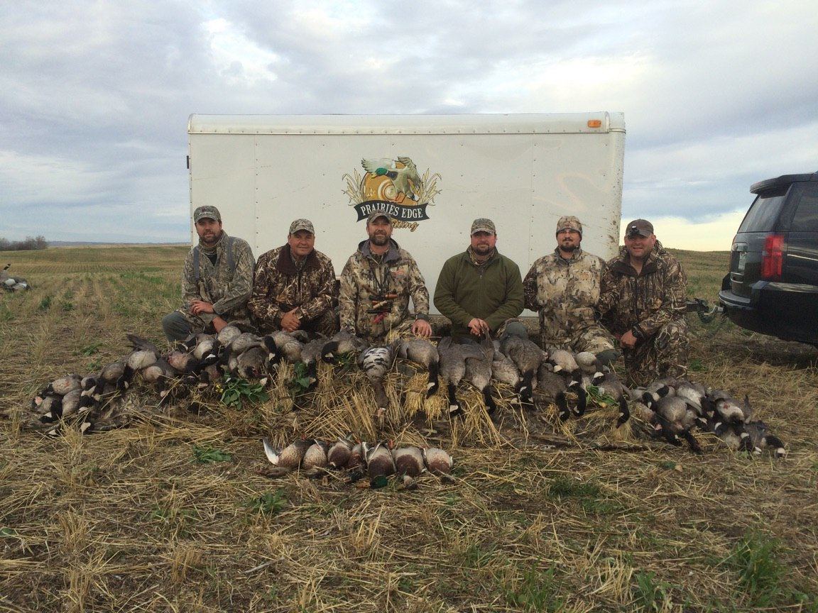 Saskatchewan waterfowl group photo with the Prairies Edge Outfitting trailer and a mixed-bag harvest